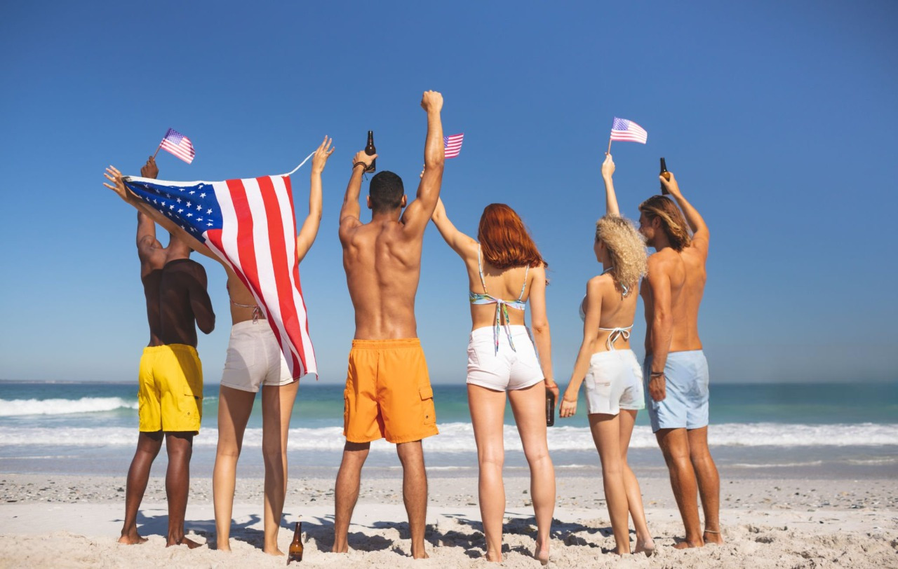 group of friends raising hands on the beach