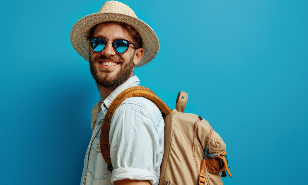 a man wearing a straw hat and sunglasses is smiling and holding a backpack