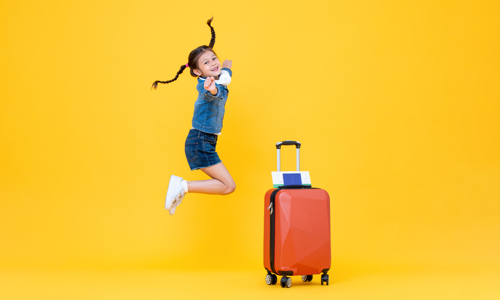 jumping excited cute little girl with luggage in isolated