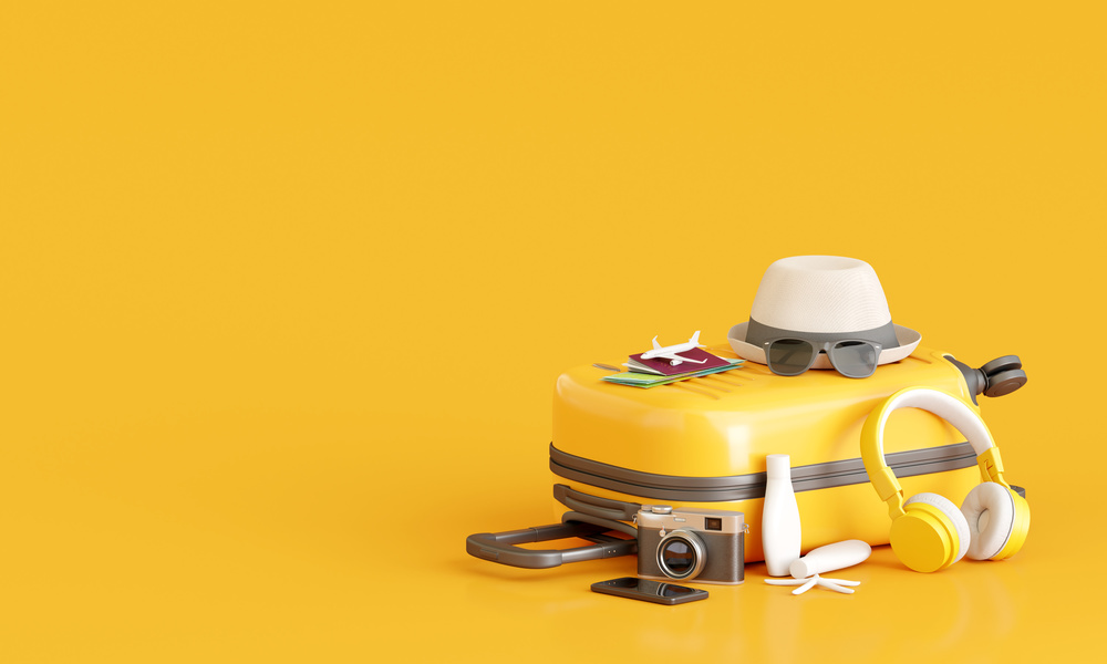 suitcase with traveler accessories on yellow background