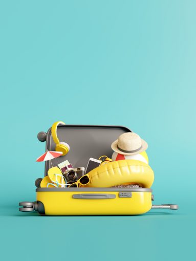 yellow suitcase with traveler accessories on blue background